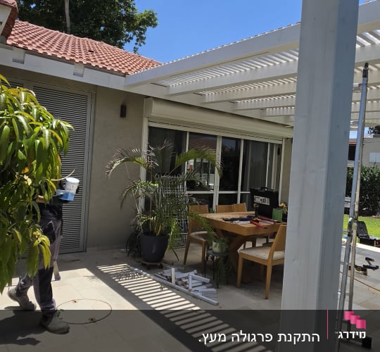 פרגולה בחצר עם שולחן וכיסאות